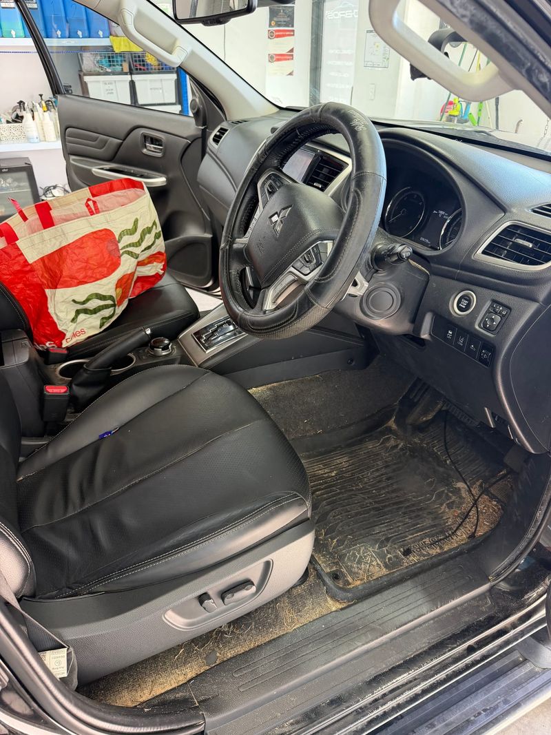 A Mitsubishi Triton's cabin before a J-Bros Interior Deep Clean, with dirt and grass through the passenger footwell
